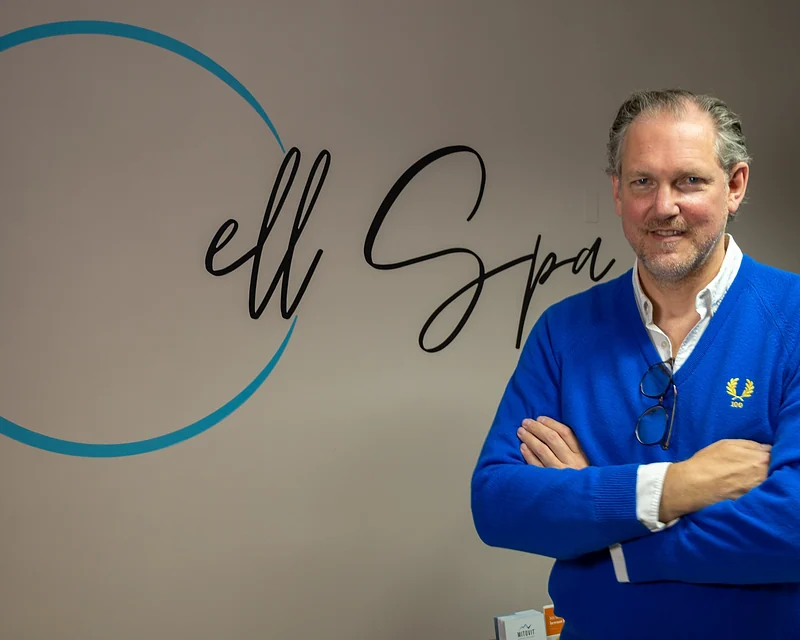 Dr. med. Carl Peter Meschede vor dem Cell-Spa-Logo in den Praxisräumen