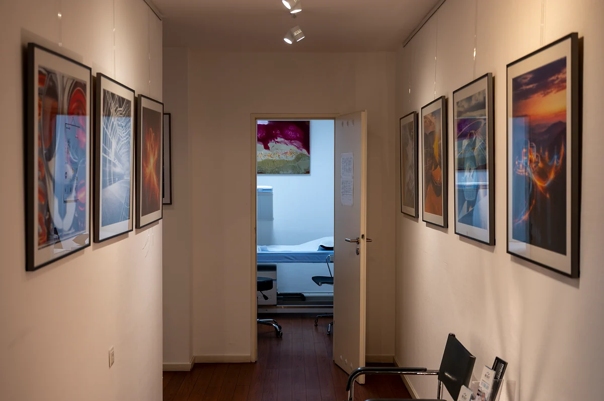 Flur der Praxis mit gerahmten Fotografien, Blick in ein Behandlungszimmer